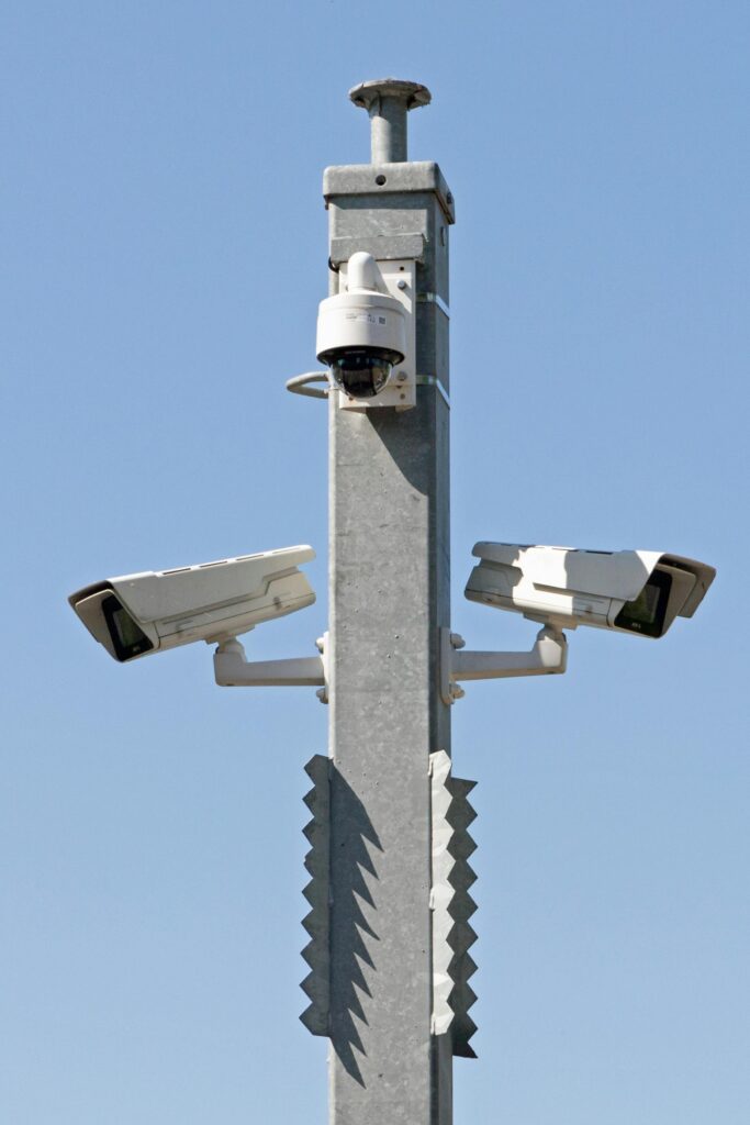 Outdoor surveillance system with multiple cameras mounted on a metal pole against blue sky.